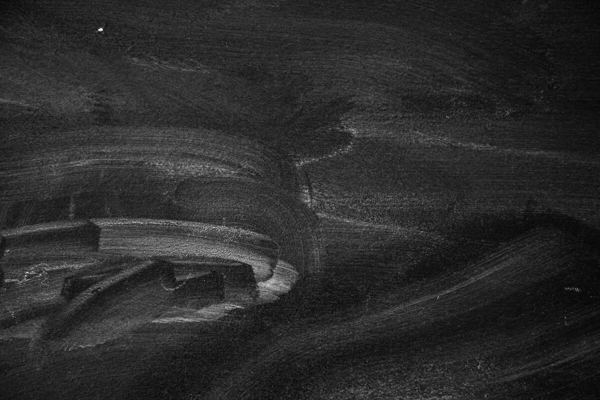 Dark blackboard surface with chalk smudges and faint erased marks