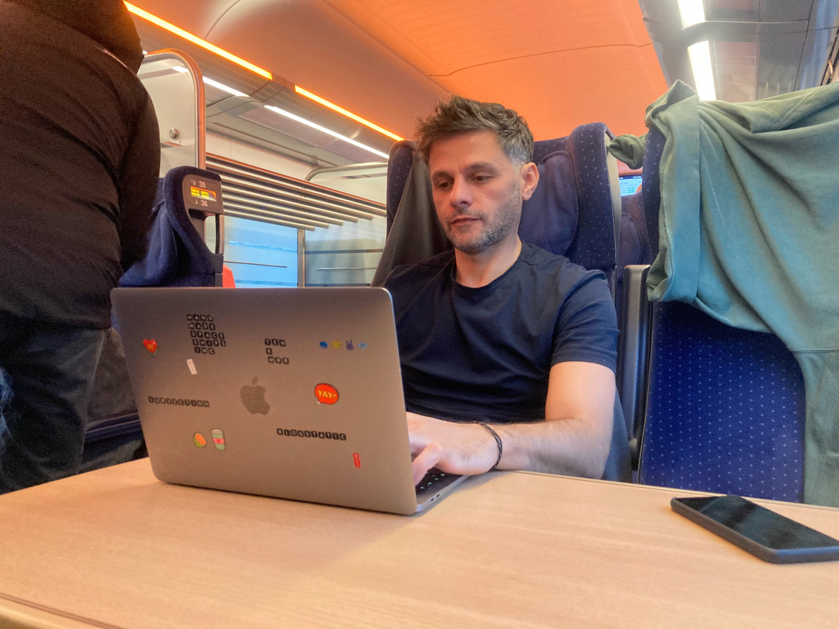 val sopi on a train sitting working on a laptop
